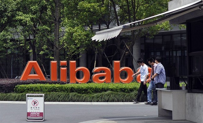 In this May 21, 2012 file photo, men walk past the corporate logo at the headquarters compound of Alibaba Group in Hangzhou in eastern China's Zhejiang province.