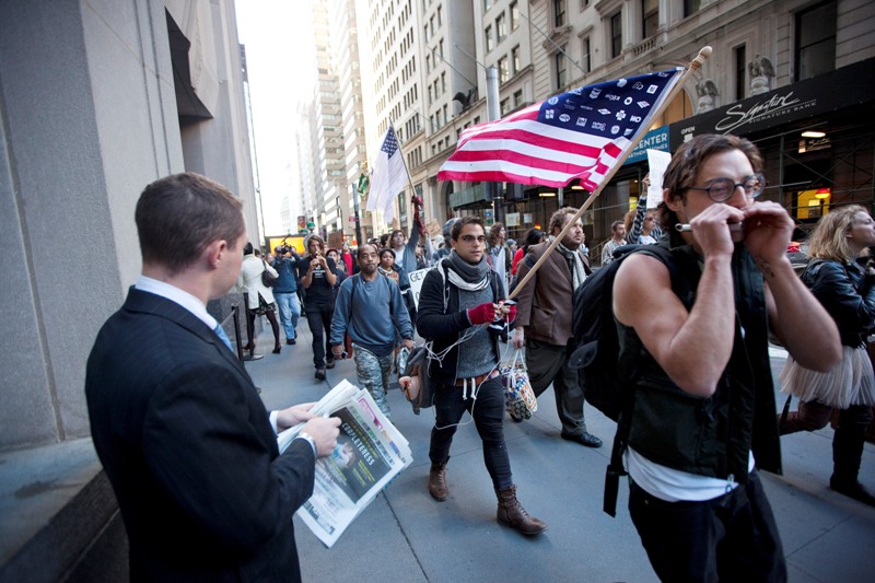 People protesting the economic system walk down a sidewalk in the financial district as office workers head to work on September 19, 2011 in New York City. Organizers said the protests, which began Saturday, could last for weeks. 