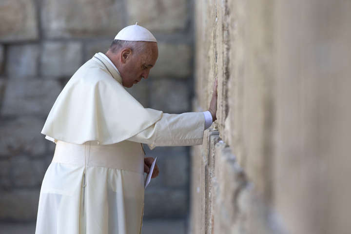 Pope Francis prays as he holds an envelope before placing it in one of the cracks between the stones of the Western Wall, the holiest place where Jews can pray, in the old city of Jerusalem, Israel, Monday, May 26, 2014. 