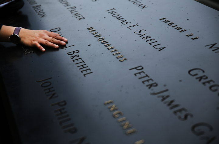 A woman places a hand on the names engraved along the South reflecting pool at the Ground Zero memorial site during the dedication ceremony of the National September 11 Memorial Museum in New York May 15, 2014 in New York City.