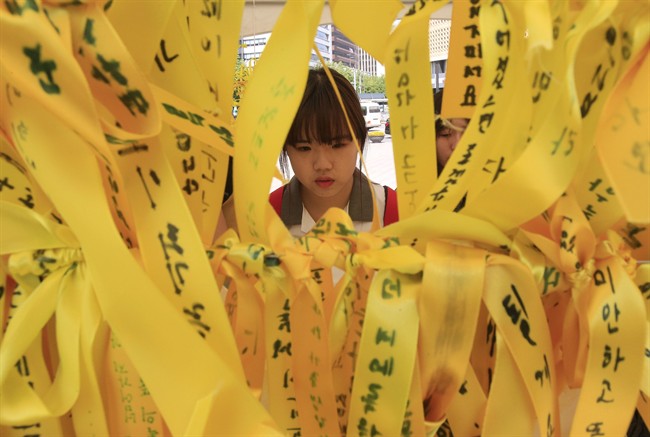 In this file photo, a high school student reads massages written on ribbons for the victims of the sunken ferry Sewol at a group memorial altar in Seoul, South Korea, Thursday, May 15, 2014. 