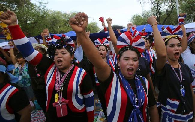 Anti-government protesters raise fists as they sing and listen to the national anthem during a gathering Thursday, May 22, 2014 in Bangkok, Thailand. Thailand\’s army chief announced a military takeover of the government Thursday, saying the coup was necessary to restore stability and order after six months of political deadlock and turmoil.