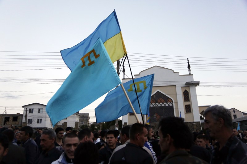 Crimean Tatars hold a Ukrainian and Tatar flags as they attend a memorial ceremony marking the 70th anniversary of the deportation of Tatars from Crimea, near a Mosque in Simferopol on May 17, 2014.  AFP PHOTO / MAX VETROV .