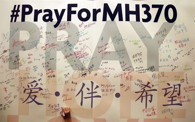 FILE - In this April 6, 2014 file photo, a man writes messages for passengers aboard the missing Malaysia Airlines Flight MH370 before a mass prayer for them, in Kuala Lumpur, Malaysia.