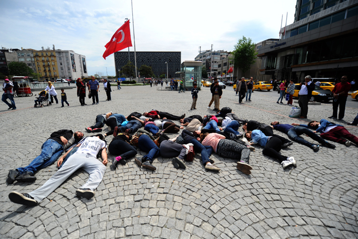 Protesters lie down, acting as dead miners in front of a Turkish flag at half mast at Taksim square in Istanbul.