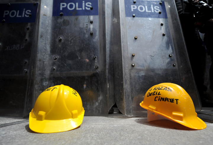 Protestors leave miner helmets front of riot police shields in Istanbul. The helmets said ‘not an industrial accident, murder.’