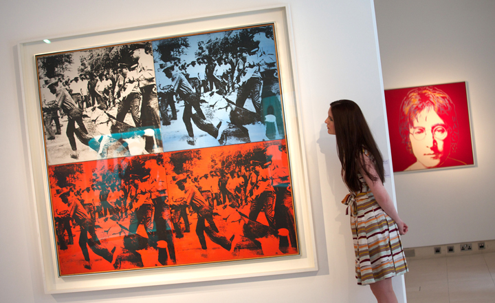 A Christie's employee looks at "Race Riot" by Andy Warhol during a photo call in central London on April 11, 2014.