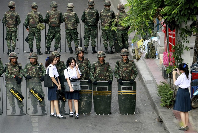 Thai school girls have their photographs taken with soldiers guarding the area to prevent anti-coup demonstration at Victory Monument in Bangkok, Thailand Thursday, May 29, 2014. 