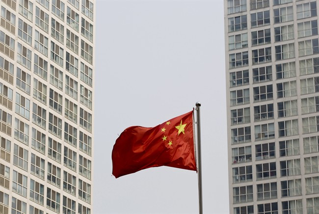 A Chinese national flag flutters in the wind in between a high-rise residential and office complex in Beijing, China Monday, May 19, 2014.