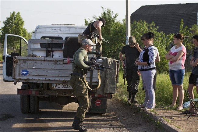 Pro-Russian men jump from a vehicle to support their comrades as local citizen look at them at a checkpoint outside Slovyansk, eastern Ukraine, Thursday, May 15, 2014. 