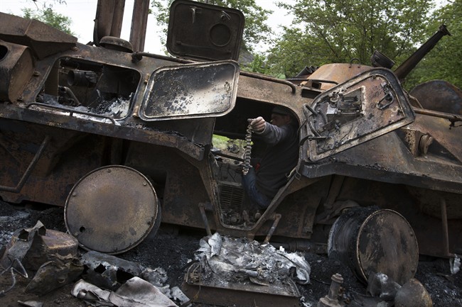 A local citizen holds a machine-gun belt as others collect parts of a seized APC that was set alight during a fighting between pro-Russian militants and government troops at Oktyabrskoye village, about 20 km. (12 miles) from Kramatorsk, eastern Ukraine, Wednesday, May 14, 2014. 