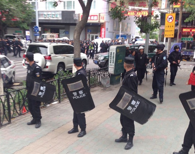 In this photo released by China's Xinhua News Agency, police officers stand guard near a blast site which has been cordoned off, in downtown Urumqi, capital of northwest China's Xinjiang Uygur Autonomous Region, Thursday, May 22, 2014.