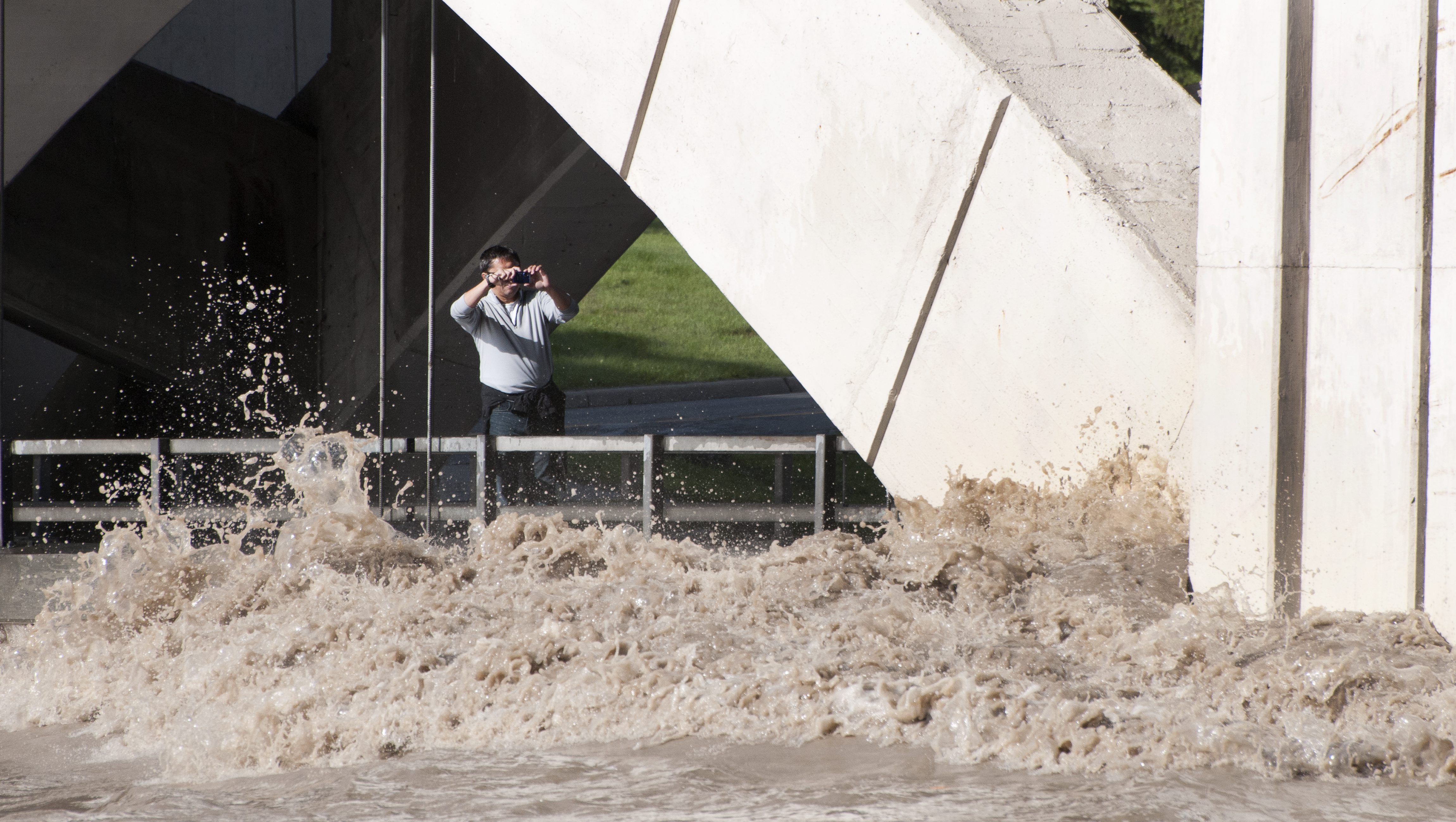 After crossing police warning tape, a spectator walks out onto the Centre Street bridge lower deck to photograph the raging flood waters of the Bow River near downtown on June 21, 2013. THE CANADIAN PRESS IMAGES/Larry MacDougal
