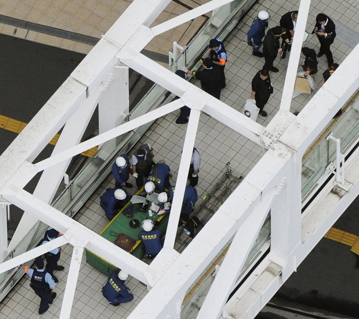 Investigators and firefighters work at the scene where a man has set himself on fire, on a pedestrian walkway at Tokyo's busy Shinjuku railway station,  Sunday.