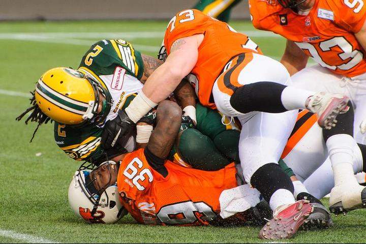 Fred Stamps #2 of the Edmonton Eskimos gets stopped by Josh Johnson #39 and Alex Hoffman-Ellis #73 of the BC Lions during a CFL game at Commonwealth Stadium on June 13, 2014 in Edmonton, Alberta, Canada.