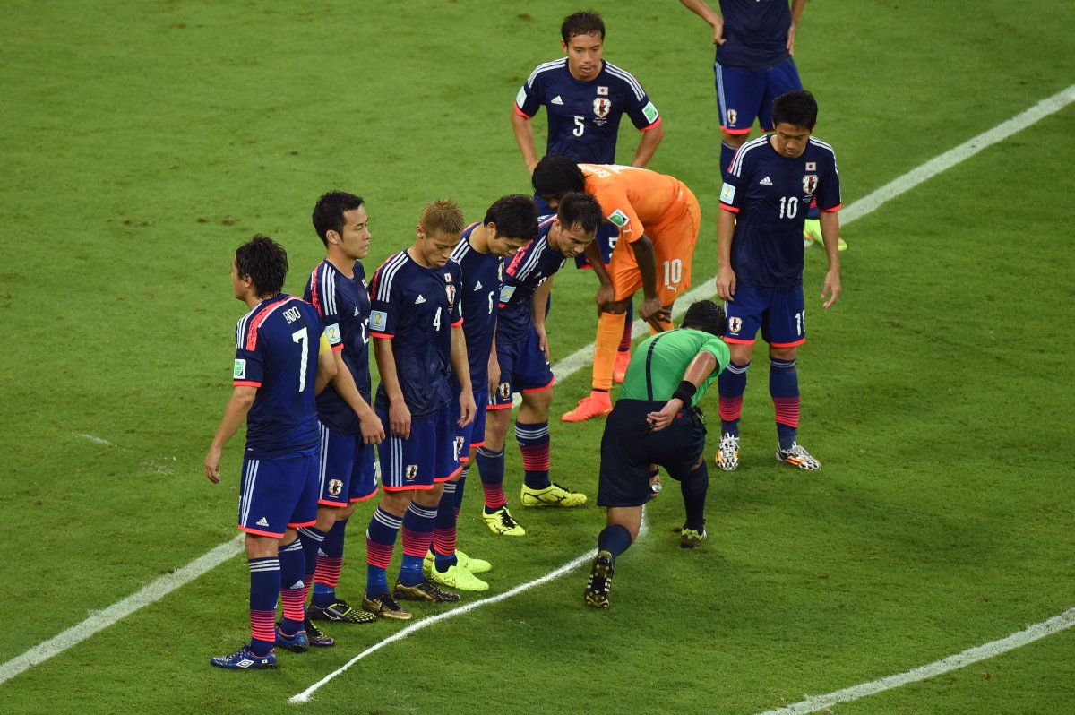 Referee Enrique Osses sprays a temporary line for a free kick as Japan forms a wall during the 2014 FIFA World Cup match  between the Ivory Coast and Japan at Arena Pernambuco on June 14, 2014 in Recife, Brazil.  