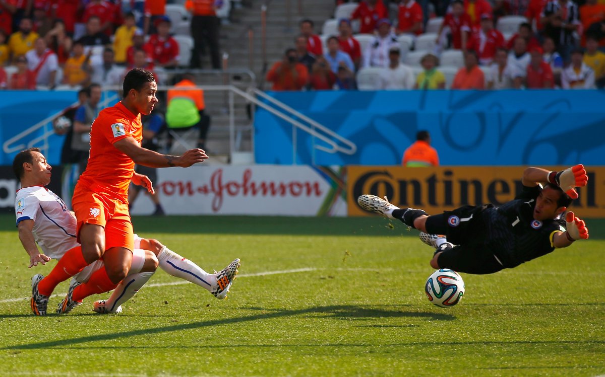 Netherlands player Memphis Depay shoots past Chile goalkeeper Claudio Bravo to score his team's second goal on June 23, 2014.