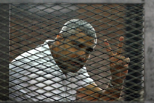 Mohammed Fahmy gestures from the defendant's cage during a sentencing hearing in a courtroom in Cairo, Egypt, in June 2014.