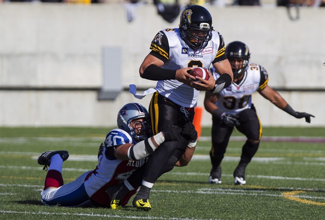 Hamilton Tiger-Cats quarterback Jeremiah Masoli, centre, attempts to shake off the tackle from Montreal Alouettes' Ameet Pall during pre-season CFL action in Hamilton, Ont., Saturday, June 14, 2014. 