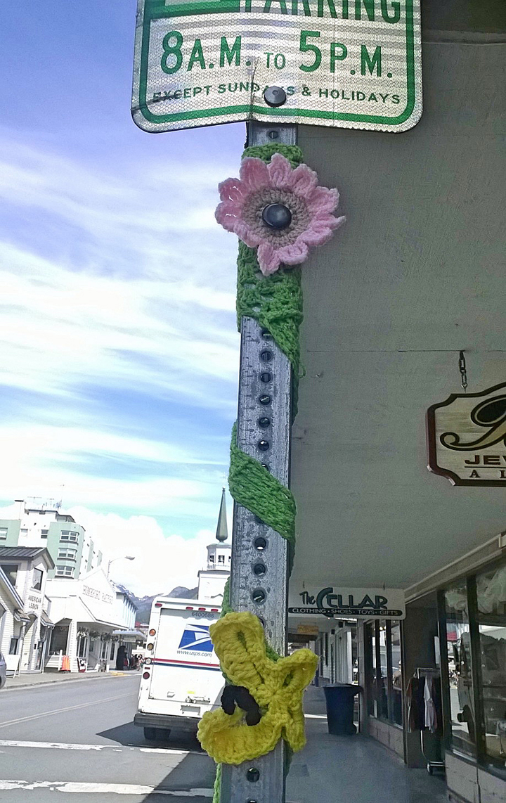 In this June 12, 2014 photo provided by Fran Hartman, the pole of a street sign is adorned with a pair of yarn flowers in Sitka, Alaska.