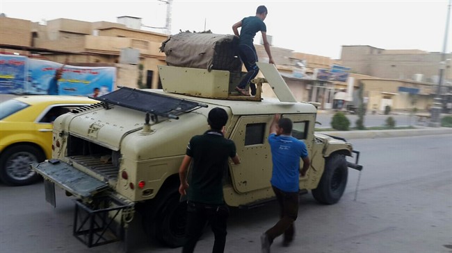 Teenagers ride on an armoured vehicle belonging to the Iraqi army in Tikrit, 130 kilometres north of Baghdad, Iraq, Wednesday, June 11, 2014. 