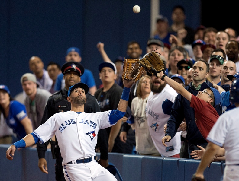 Toronto Blue Jays Jose Bautista has a fan interfere with a foul pop-fly by St. Louis Cardinals Tony Cruz during ninth inning inter-league action in Toronto on Friday June 6, 2014. THE CANADIAN PRESS/Frank Gunn.