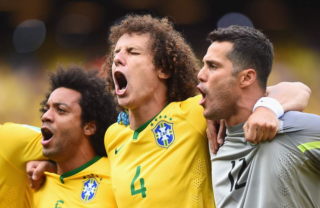 FORTALEZA, BRAZIL - JUNE 17: David Luiz of Brazil (center) sings the National Anthem with Marcelo and Julio Cesar before the 2014 FIFA World Cup Brazil Group A match between Brazil and Mexico at Castelao on June 17, 2014 in Fortaleza, Brazil. (Photo by Laurence Griffiths/Getty Images)
