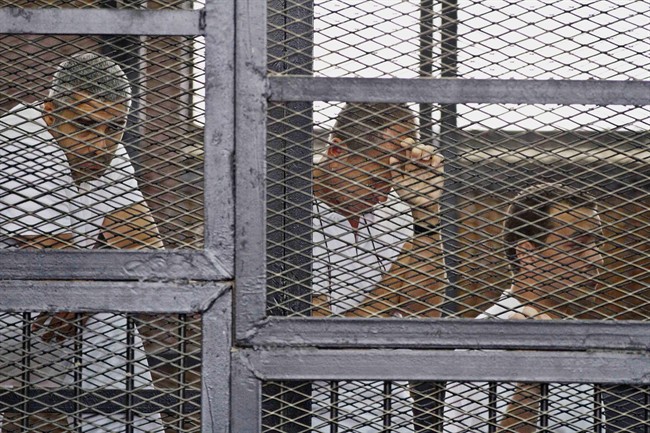 In this Thursday, May 15, 2014 file photo, from left, Mohammed Fahmy, Canadian-Egyptian acting bureau chief of Al-Jazeera, Australian correspondent Peter Greste, and Egyptian producer Baher Mohamed appear in a defendant's cage along with several other defendants during their trial on terror charges in a Cairo courtroom. Grests has recently been released from prison.
