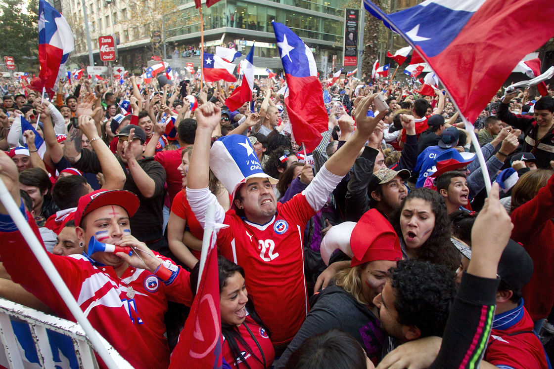 Chilean fans celebrate their team's victory over Spain in their FIFA World Cup Group Stage - Group B match, in the streets of Santiago, on June 18, 2014. AFP PHOTO / CLAUDIO REYES (Photo credit should read Claudio Reyes/AFP/Getty Images)