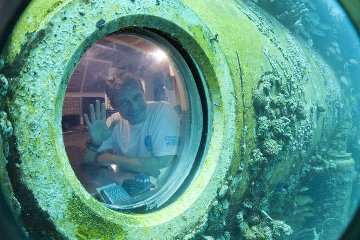 Fabien Cousteau waves from inside Aquarius Reef Base, a laboratory 63 feet below the surface in the waters off Key Largo, in the Florida Keys National Marine Sanctuary, Tuesday, June 24, 2014. 