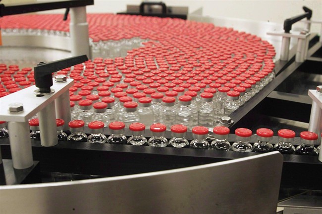 Bottles of flu vaccine rotate on a plate as they make their way through an assembly line on Dec. 9, 2004.