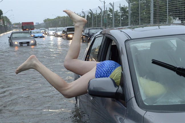 A woman gets back in her car in flood water on Lakeshore West during a storm in Toronto on Monday, July 8, 2013. 