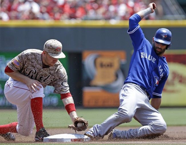 Toronto Blue Jays' Jose Bautista, right, advances safely to third base as Cincinnati Reds third baseman Todd Frazier applies the tag in the first inning of a baseball game on Sunday, June 22, 2014, in Cincinnati.
