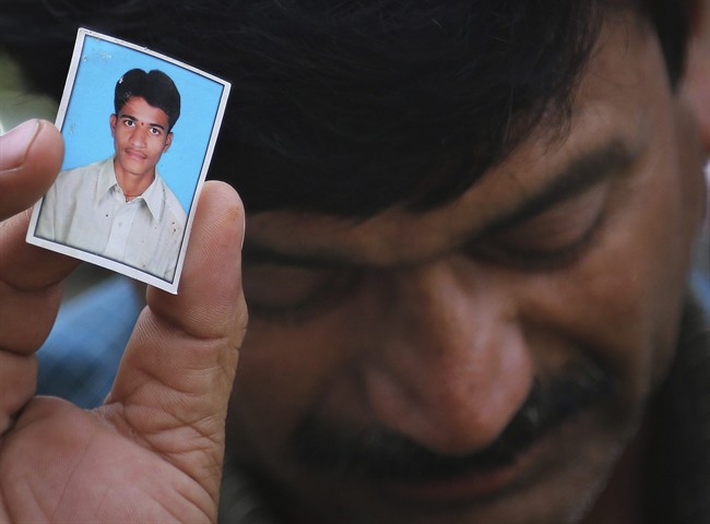 Bonath Shekar Naik shows a portrait of his son Rambabu, only one name available, one of the 24 students feared dead during a field trip near the mountain resort town of Manali, India, Monday, June 9, 2014. 
