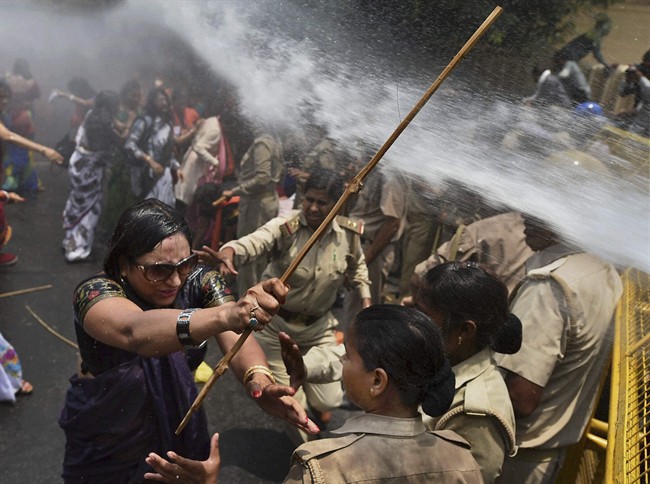 An Indian woman, left, one among the protestors demonstrating outside the office of Uttar Pradesh state chief minister Akhilesh Yadav, demanding that he crack down on an increasing number of rape and other attacks on women and girls, scuffles with police in Lucknow, India, Monday, June 2, 2014. 