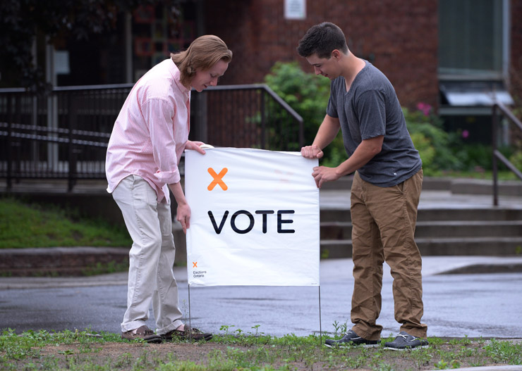 Poll station workers place a vote sign in preparation for voters on election day in Carleton Place, Ont. on Thursday June 12, 2014.