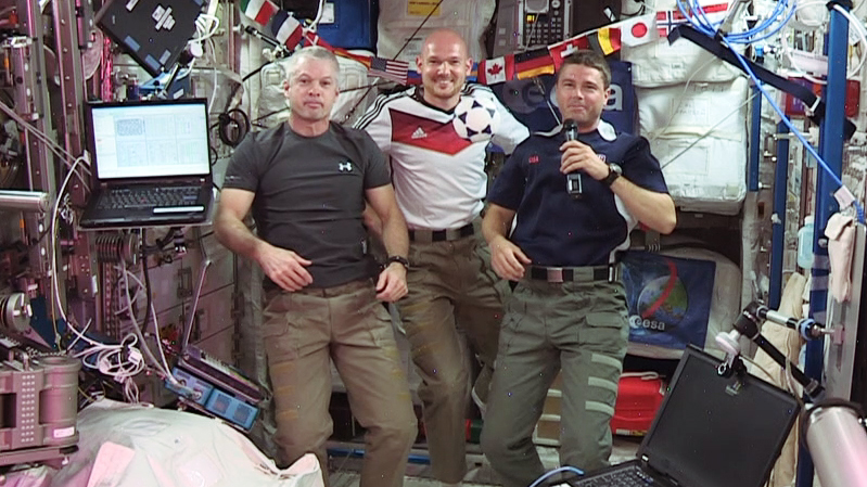 (From left) Expedition 40 Commander Steve Swanson and Flight Engineers Alexander Gerst and Reid Wiseman wish soccer fans and the World Cup 2014 “peaceful games.”