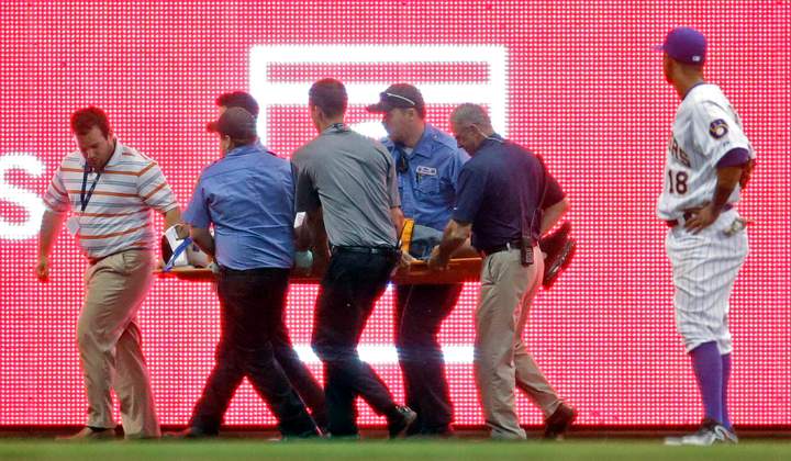 Milwaukee Brewers left fielder Khris Davis watches as a fan is helped off the field during the eighth inning of a baseball game against the Minnesota Twins Tuesday, June 3, 2014, in Milwaukee.