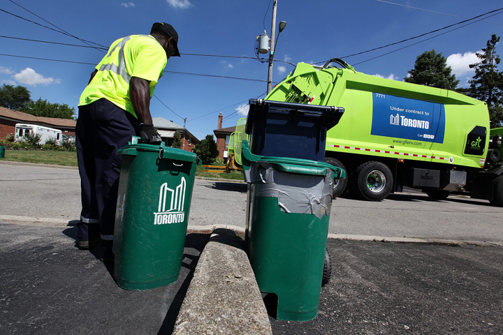 An employee of Green For Life waste collection picks up recycling and compost in the neighbourhood of Sheppard Avenue and Dufferin Street in Toronto, August 07, 2012.