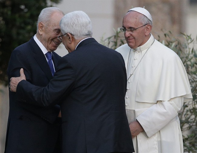 Pope Francis looks at Israel's President Shimon Peres, left, and Palestinian President Mahmoud Abbas greet each other during an evening of peace prayers in the Vatican gardens, Sunday, June 8, 2014.