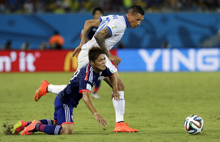 Greece's Jose Holebas, right, pulls down Japan's Yoshito Okubo while chasing the ball during the group C World Cup soccer match between Japan and Greece at the Arena das Dunas in Natal, Brazil, Thursday, June 19, 2014.