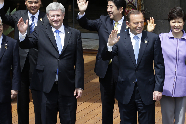 Canada's Prime Minister Stephen Harper and Australia's Prime Minister Tony Abbott (foreground) wave as they take part in the traditional 'leaders' family photo' on the final day of the Asia-Pacific Economic Cooperation (APEC) Summit in Nusa Dua on the Indonesian resort island of Bali on October 8, 2013.