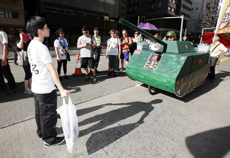 A Pro-democracy activist re-enacts an iconic moment from the pro-democracy movement protests of 1989, when a young man blocked the path of Chinese tanks, during a march marking the 25th anniversary of the Tiananmen Square massacre on June 1, 2014 in Hong Kong. (Photo by Jessica Hromas/Getty Images).