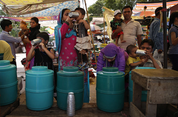 Indians quench their thirst with chilled water freely provided by traders at a market in New Delhi, India, Wednesday, June 11, 2014. 