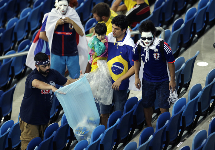 Japan supporters collect rubbish on the stands after the group C World Cup soccer match between Japan and Greece at the Arena das Dunas in Natal, Brazil, Thursday, June 19, 2014. 