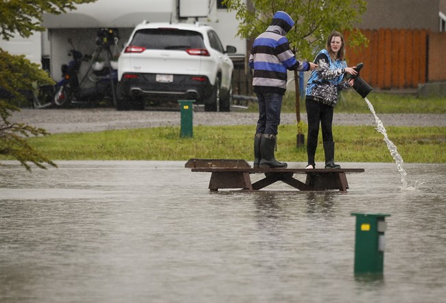 A teenager pours water out of her boot after wading through flood waters in a park in Claresholm, Alta., Wednesday, June 18, 2014.