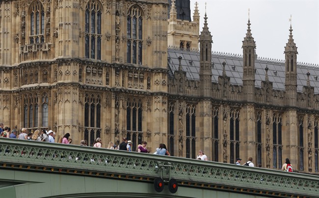 People stand on the Westminster Bridge, over the river Thames, backdropped by the Houses of Parliament in central London, Thursday, June 19, 2014.