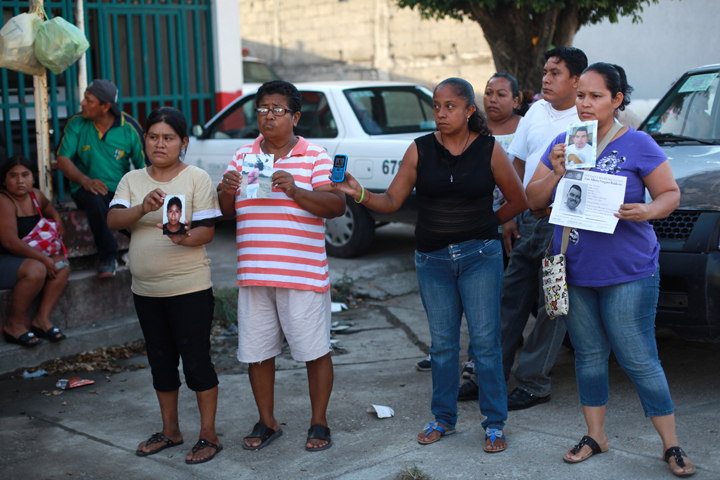 People hold portraits of their missing loved ones in front of the morgue of Cosamaloapan, with the hope of finding and identifying the bodies of their missing, from a mass grave which has been recently discovered, in Veracruz , Mexico, Wednesday, June 18, 2014. 