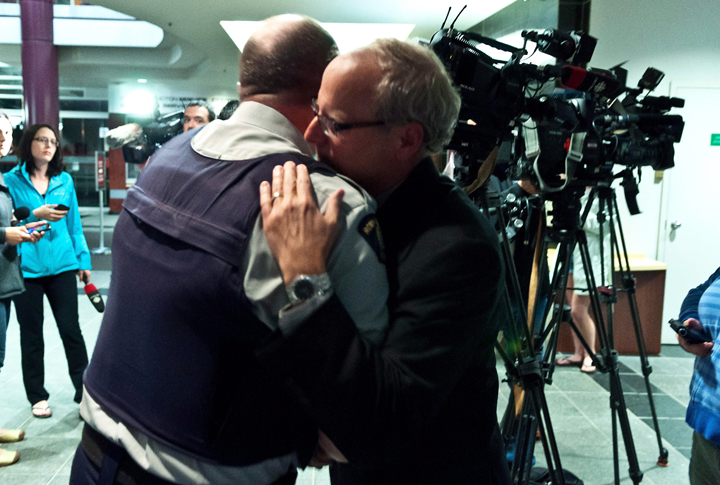 RCMP officer Damien Theriault, left, and Mayor George LeBlanc hug after addressing the media during a late press conference at City Hall in Moncton, N.B.on Wednesday June 4, 2014.