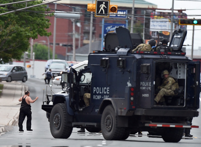 A resident of a boarding house is evacuated by emergency response officers as they search a building in Moncton, N.B. on Thursday, June 5, 2014.